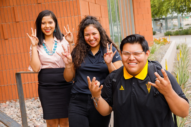 three students posing for a picture throwing up the ASU pitchfork sign with their hands